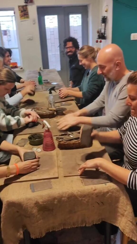 A school-sized group hand-building pottery together at the long studio table at Gilgamesh for Creative Arts, Amman