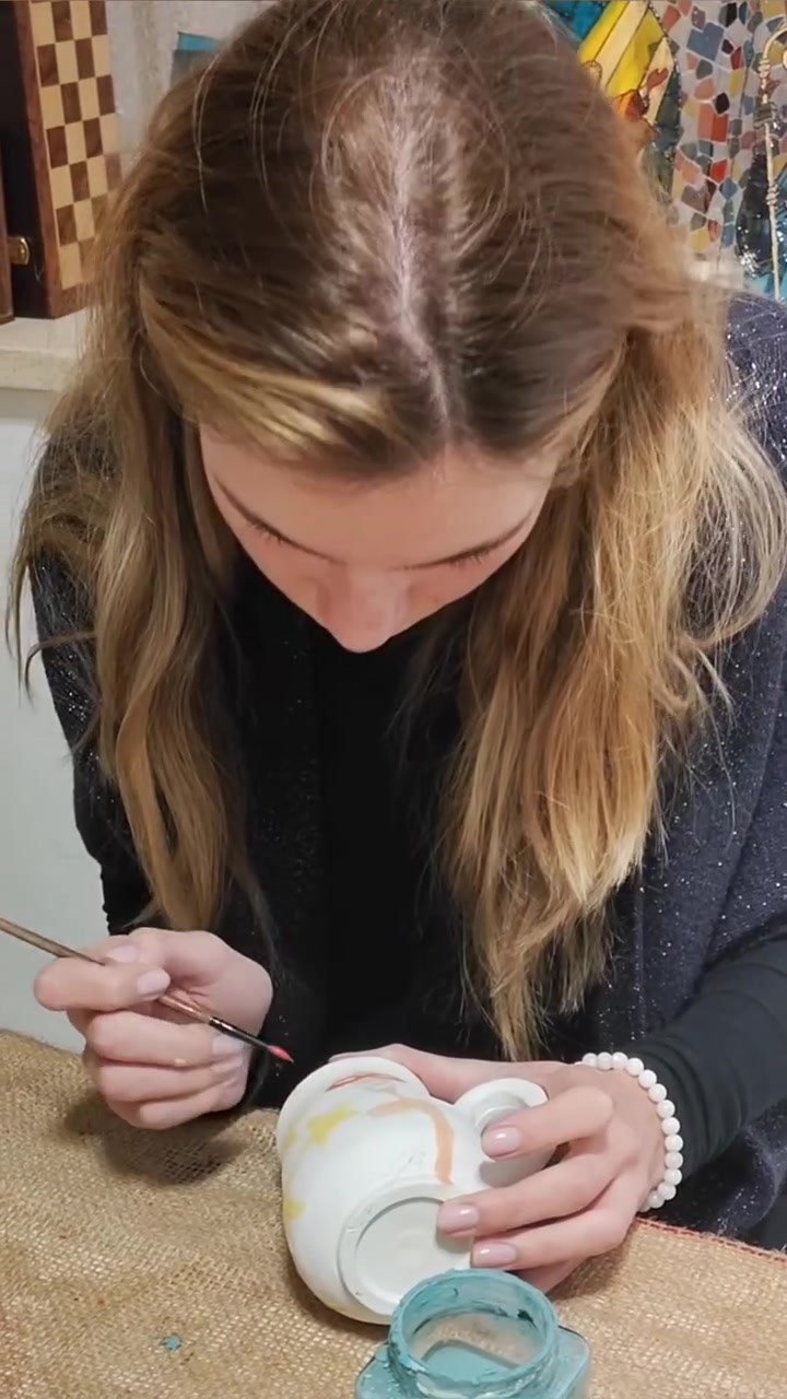 Workshop participant painting a fine design onto a white ceramic pot at Gilgamesh for Creative Arts, Jabal Al-Lweibdeh, Amman