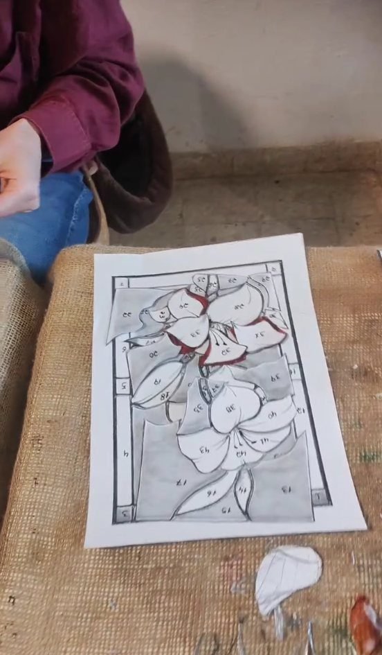 Hand-drawn paper pattern for a stained glass panel on the studio bench in Amman