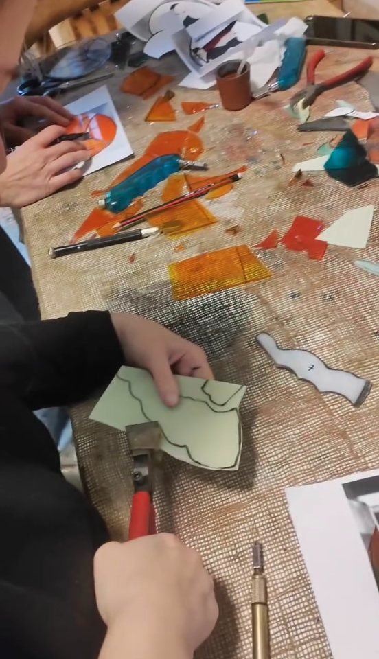Scoring and breaking glass along the pattern lines during a stained glass workshop in Amman